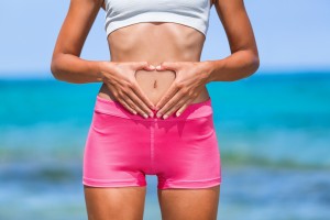 Healthy fitness woman with good stomach digestion. Hands forming heart shape. Body care, pregnancy, weight loss diet concept. Woman with intestine or reproduction problem.